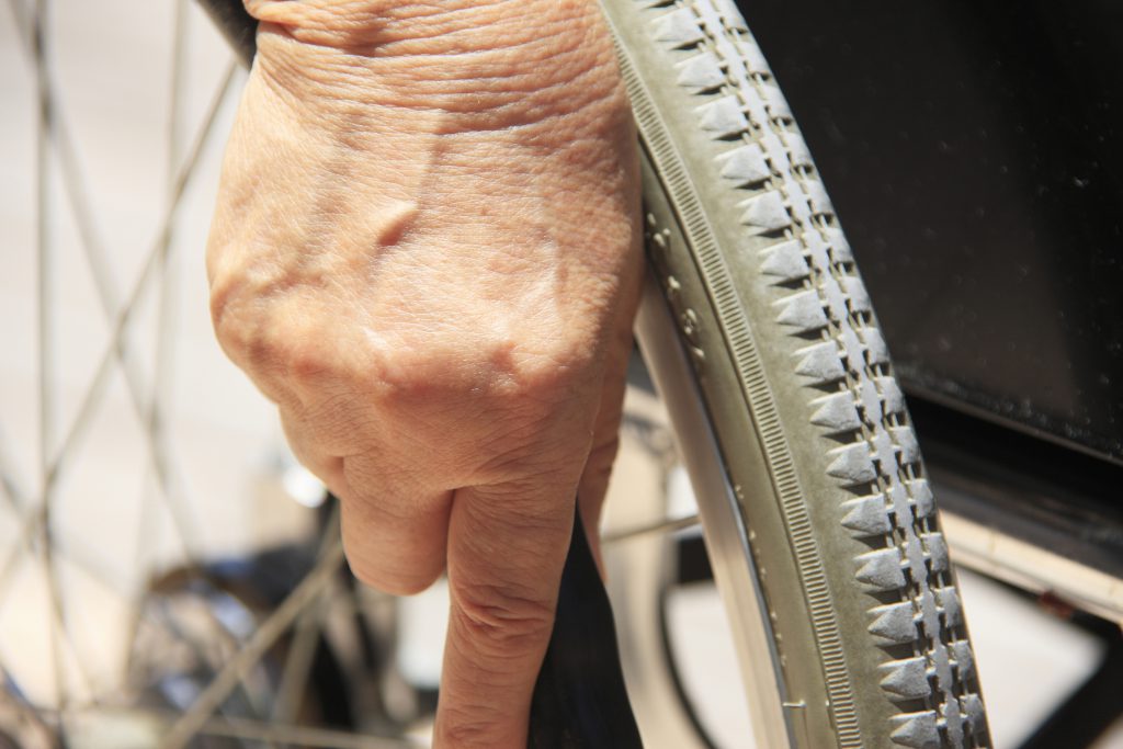 Une main de femme sur une roue de fauteuil-roulant