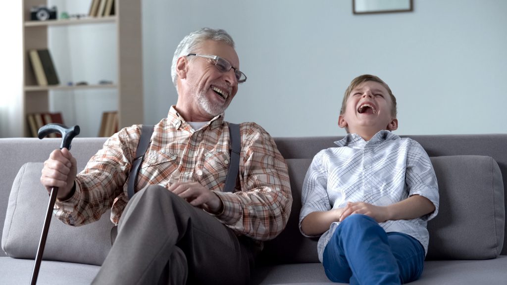 Grand-père et son petit fils ensemble assis dans un canapé