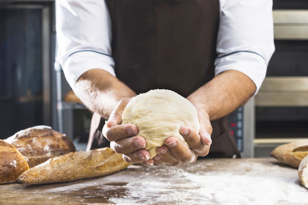 Un boulanger qui pétrit une pâte à pain sur un plan de travail fariné