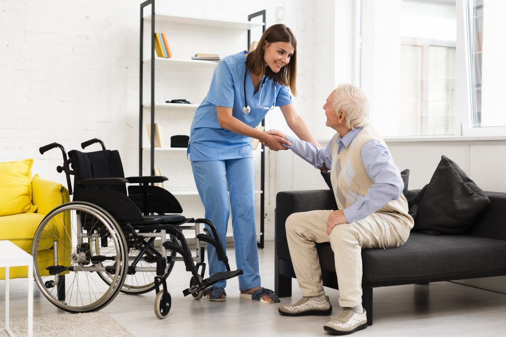 Aide-soignante aide une personne âgée à se mettre dans son fauteuil roulant.