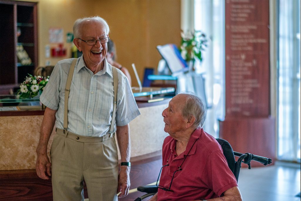 Deux seniors plaisantent ensemble dans l'entrée d'une maison de retraite. 