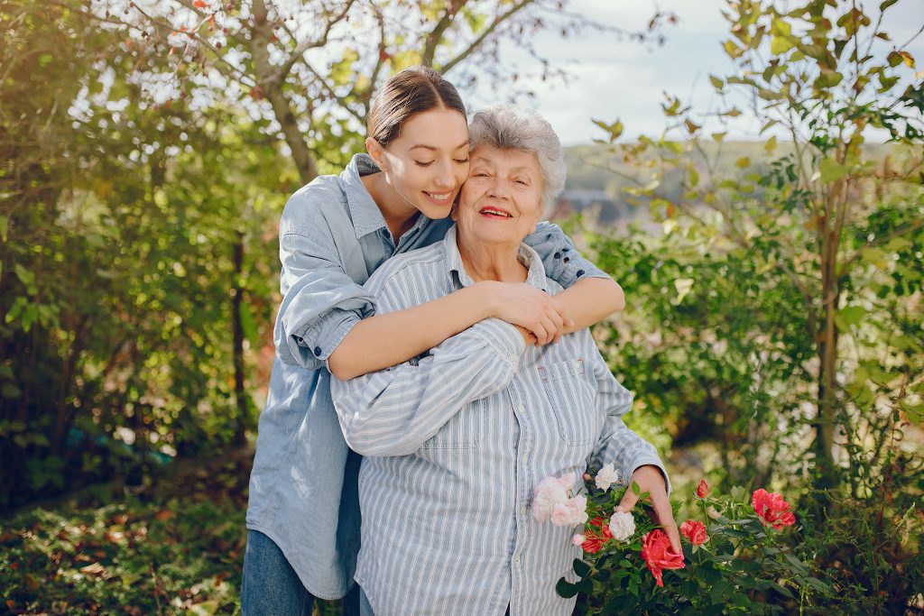 Una anciana con una flor en la mano. Mujer con una camisa azul. La abuela con la nieta.